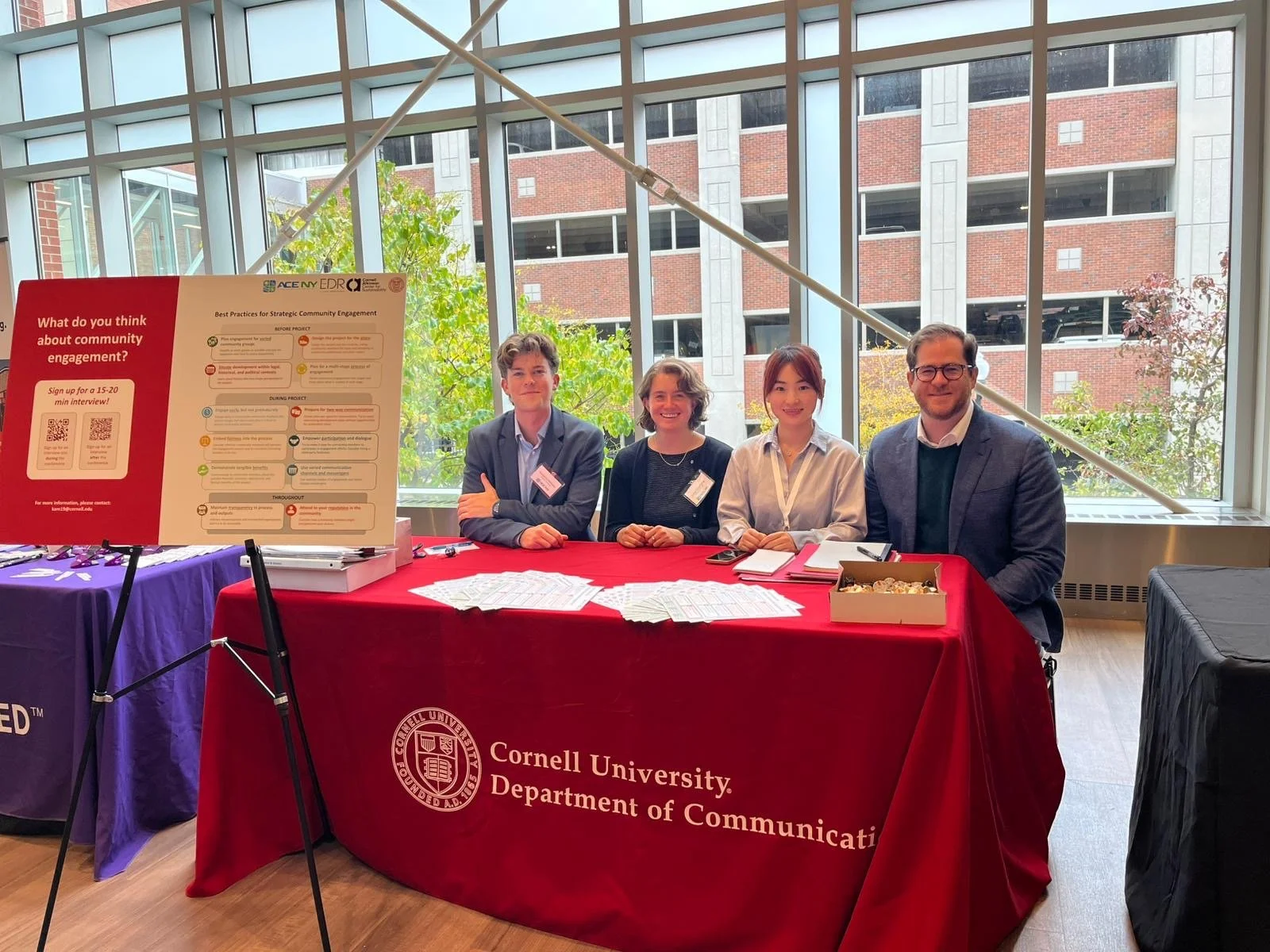 Dominic Balog-Way and three risk communication students sitting behind a table during a conference