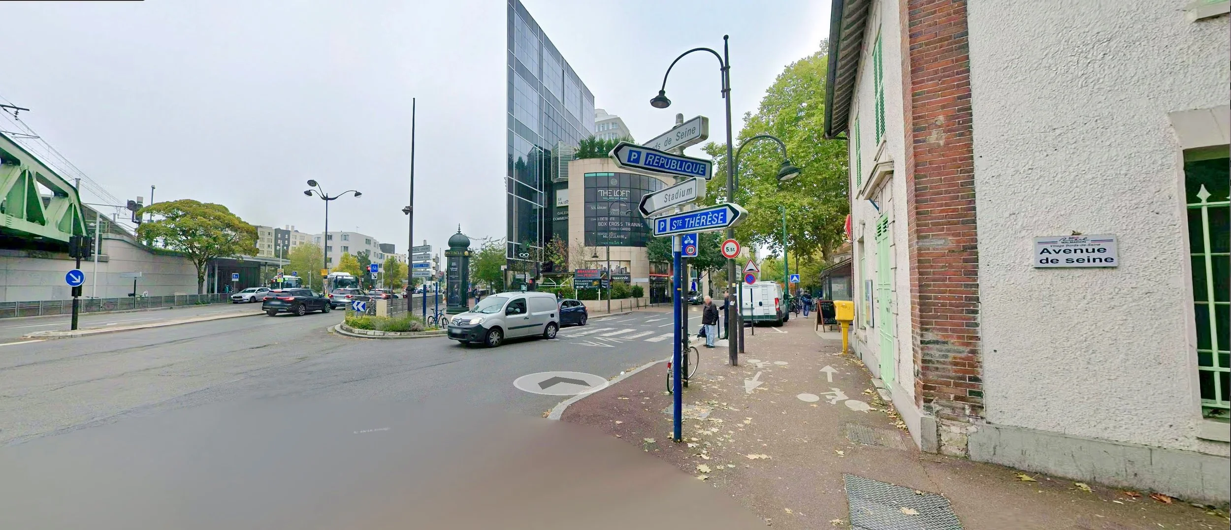 Street corner with directional signage, a bike lane, and a parked bicycle in a French town