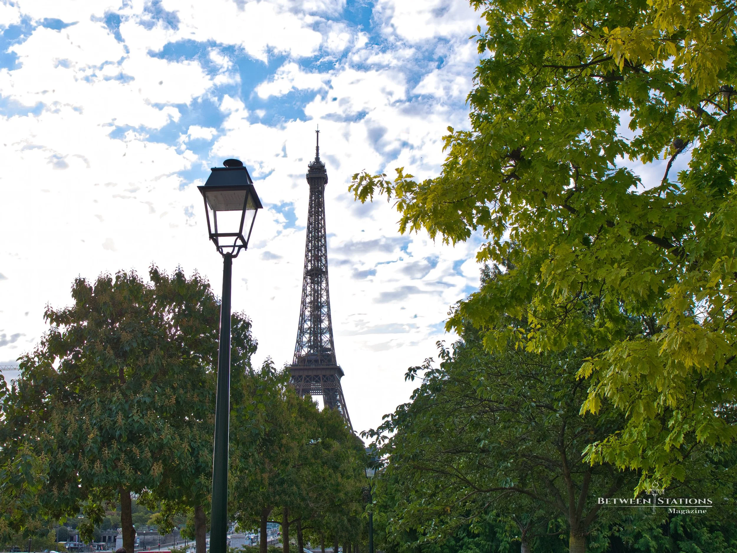 Eiffel Tower glimpsed above trees in a Parisian park in summer light