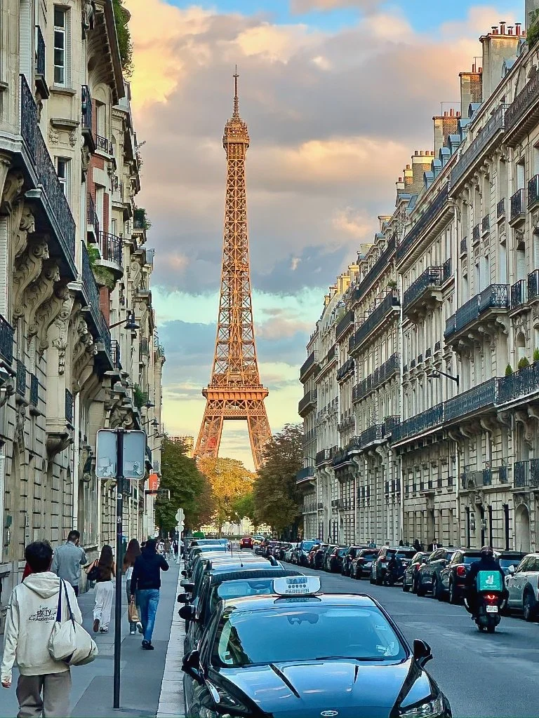 Eiffel Tower framed at the end of a Haussmannian Paris street at sunset