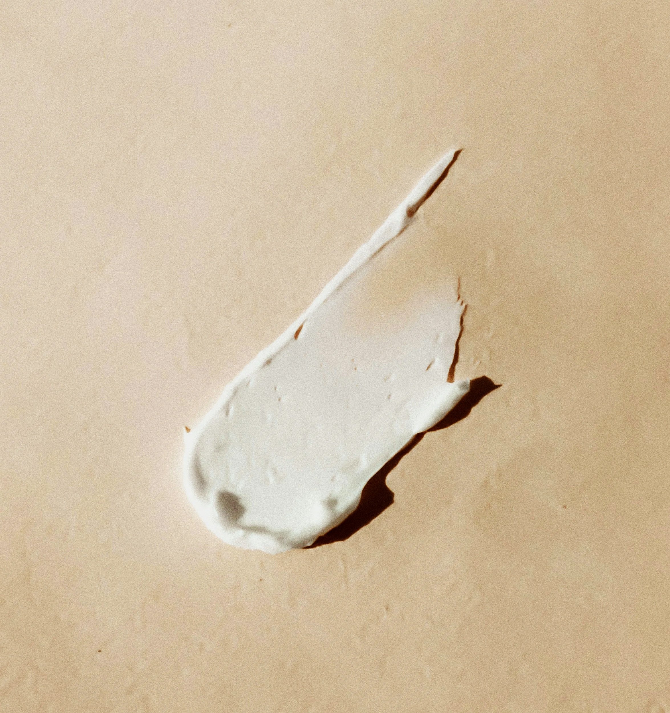 Close-up image of a torn white paper with jagged edges on a beige surface.