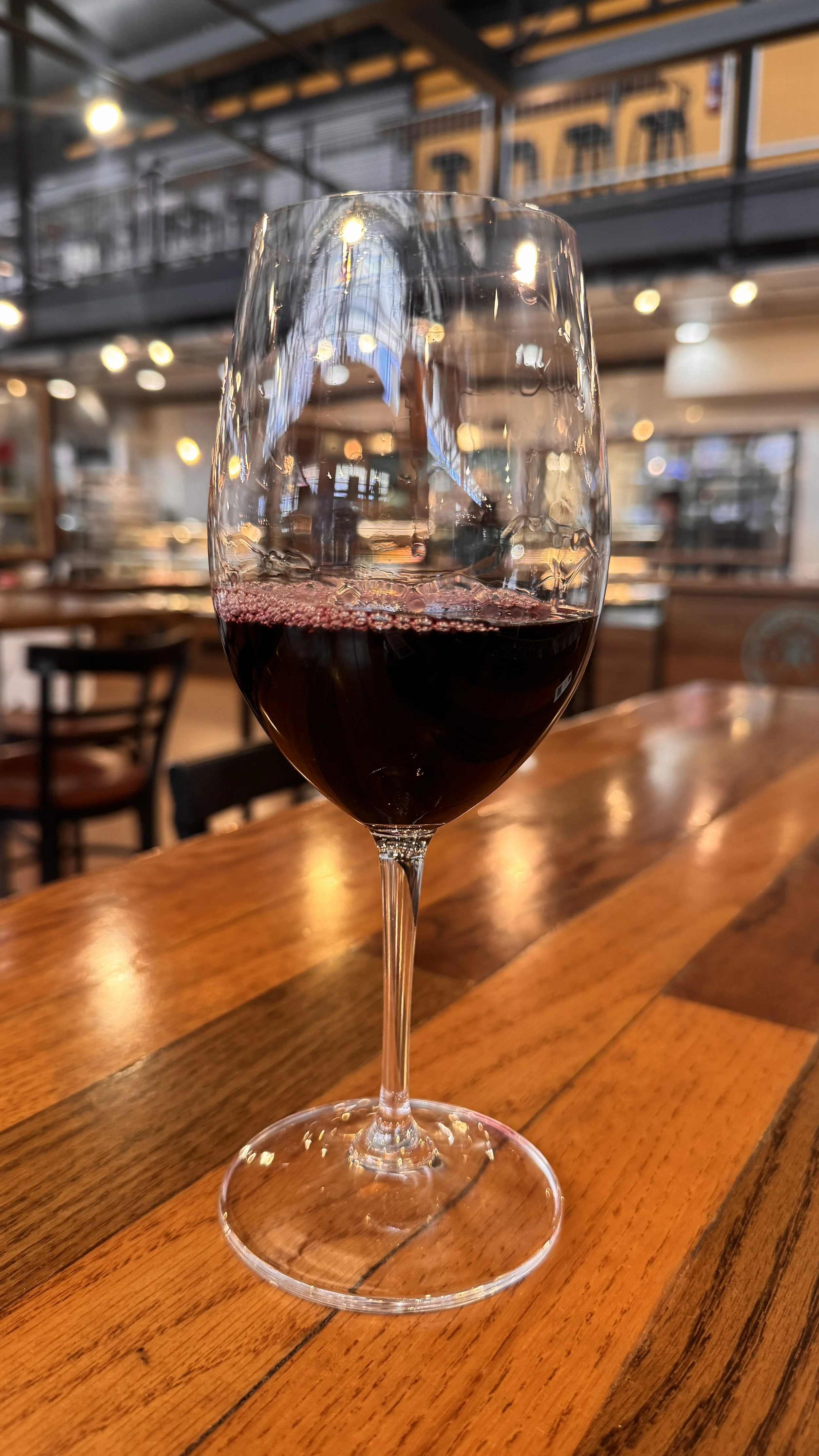 A glass of red wine on a wooden table at Thief Wine inside the Milwaukee Public Market in the Historic Third Ward of Milwaukee, Wisconsin