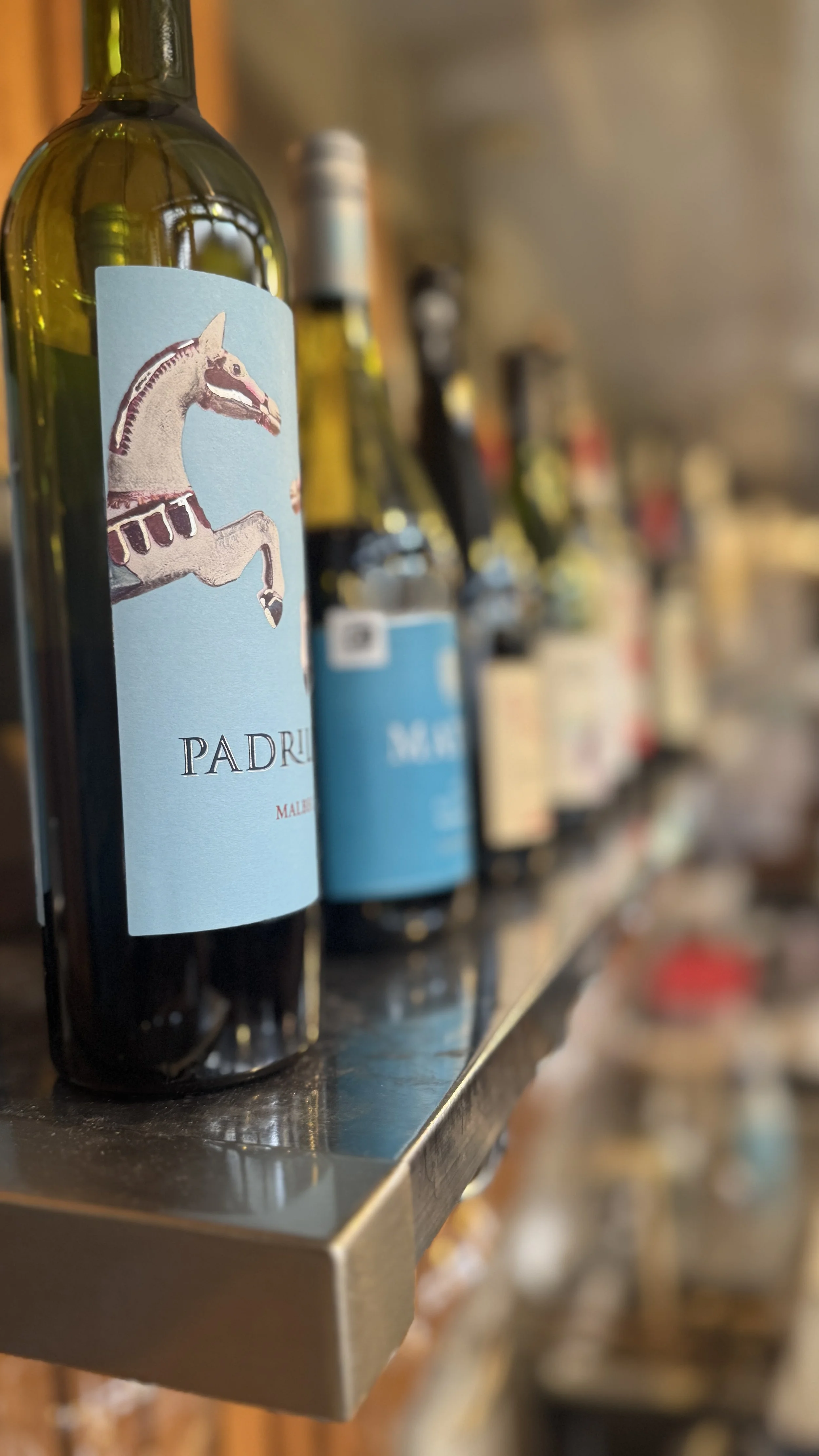 A row of wine bottles on the "wines by-the-glass" shelf at Thief Wine Shop and Bar in the Milwaukee Public Market in the Historic Third Ward of Milwaukee, Wisconsin