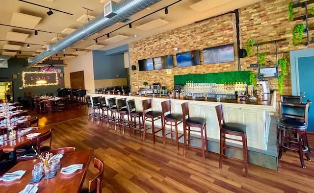 Cozy full restaurant, full service at our bar area with bar stools, a brick wall, and multiple TV screens. Open seats, immediate seating.