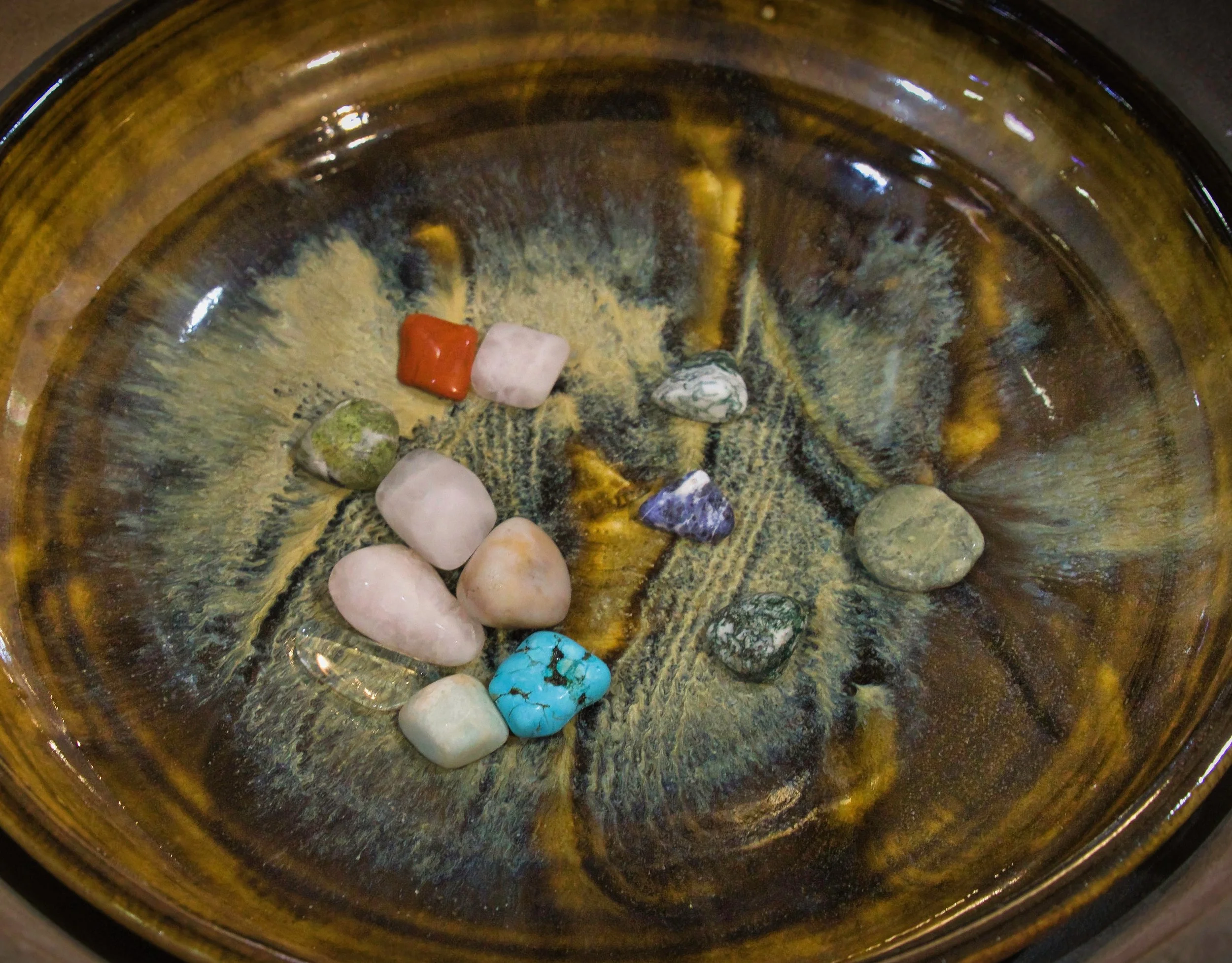 A variety of small, polished stones in different colors, shapes, and textures arranged in a bowl or container.