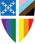 A shield divided into four quadrants with different colors and patterns: top left with plus signs on a light blue background, top right with a black diagonal stripe on a brown background, bottom left with vertical rainbow stripes, and bottom right with a yellow top stripe and a green bottom stripe.