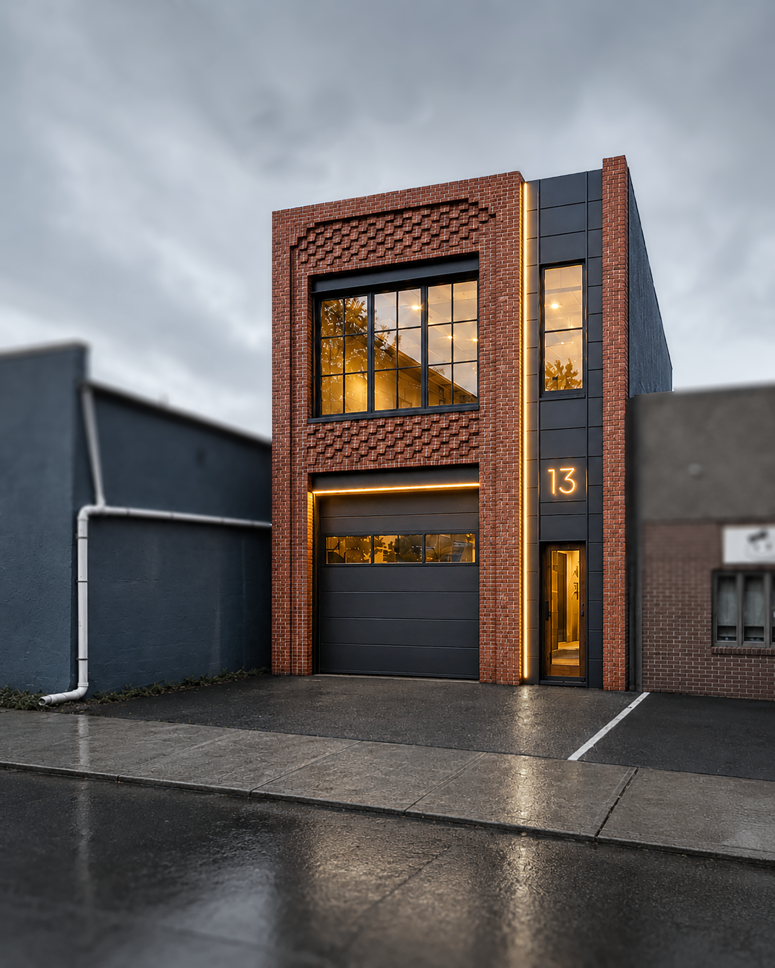 Modern brick and black building with large glass windows on the second floor, illuminated interior, and a glass door on the ground floor, with the number 13 and decorative lighting on the outer wall, adjacent to a dark parking lot with wet pavement and an overcast sky.
