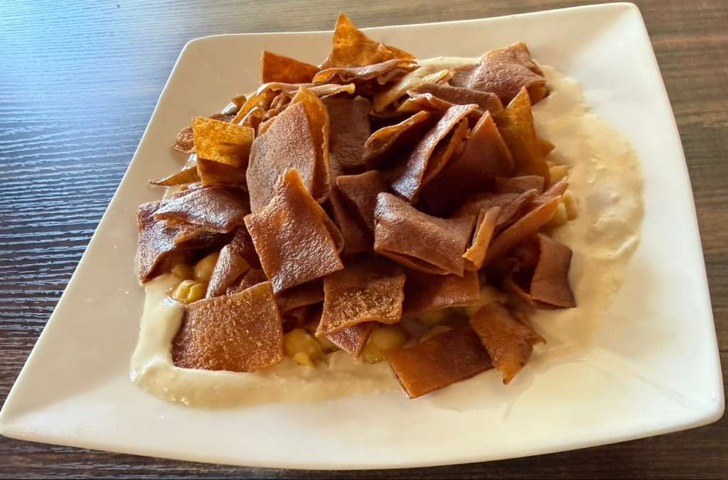 Plate of shepherd's pie with mashed potato, ground meat, and crispy fried tortilla strips on top.
