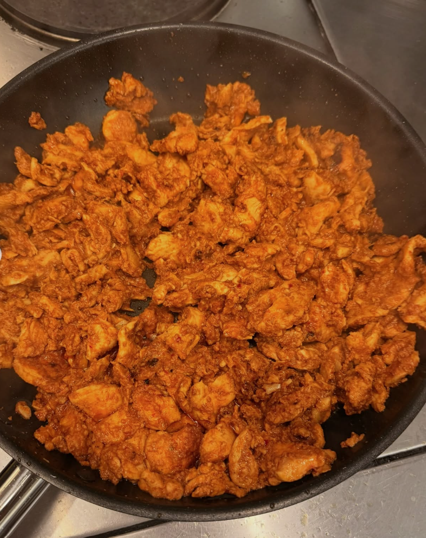 Cooked ground chicken in a seasoned tomato-based sauce in a black skillet.
