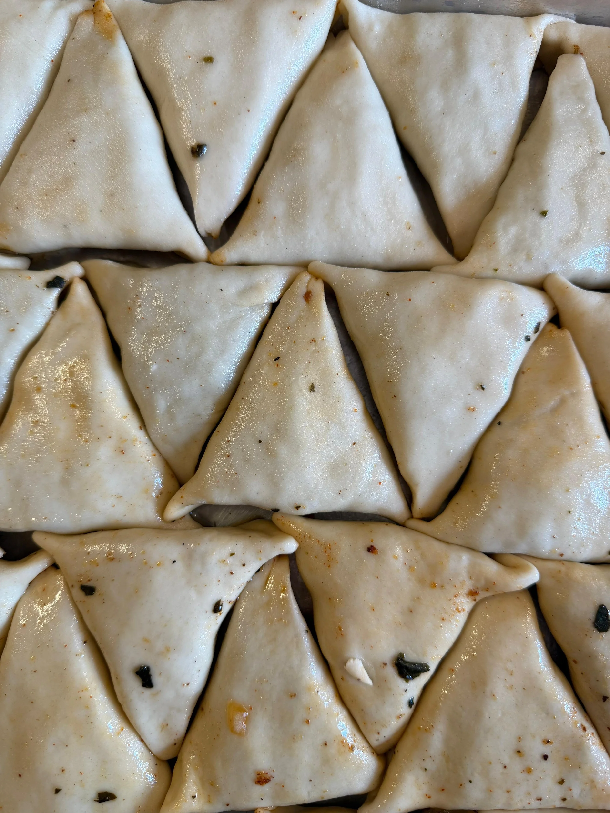 Dumplings arranged closely together, some with visible spices and herbs.