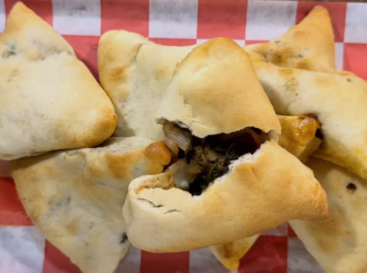 Samosa pastry with dark filling, likely vegetables or meat, on a red and white checkered paper