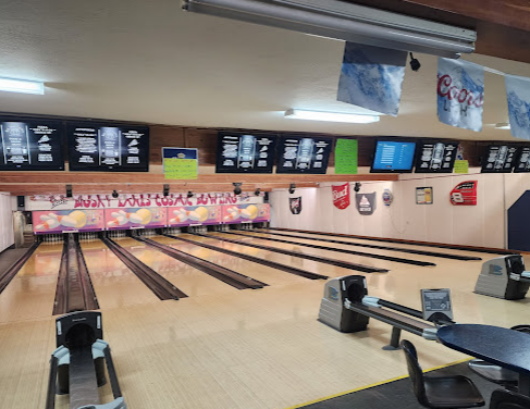Bowling alley with ten lanes, digital scoreboards, overhead decorations, and seating area.