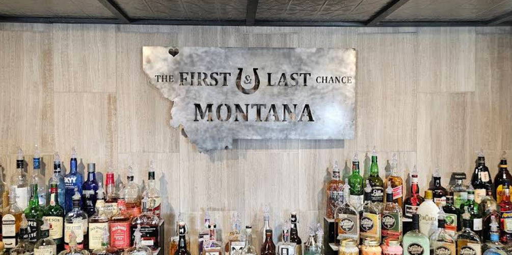 Bar with bottles of alcohol and a sign that reads 'The First & Last Chance Montana'
