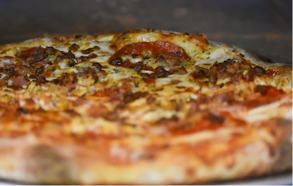 Close-up of a freshly baked pizza with cheese, pepperoni, sausage, and vegetables.