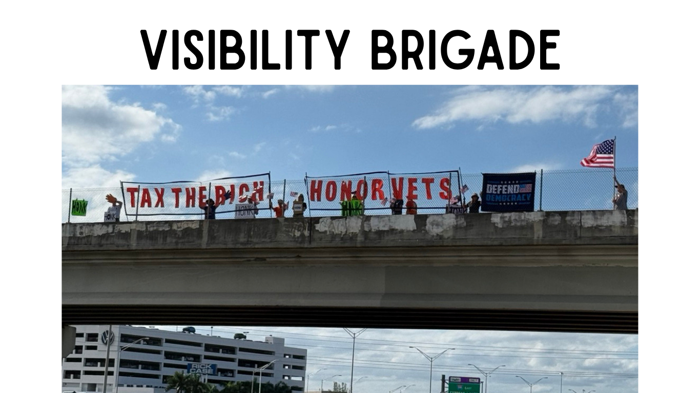 Protestors with signs on an overpass the signs say tax the rich honor vets