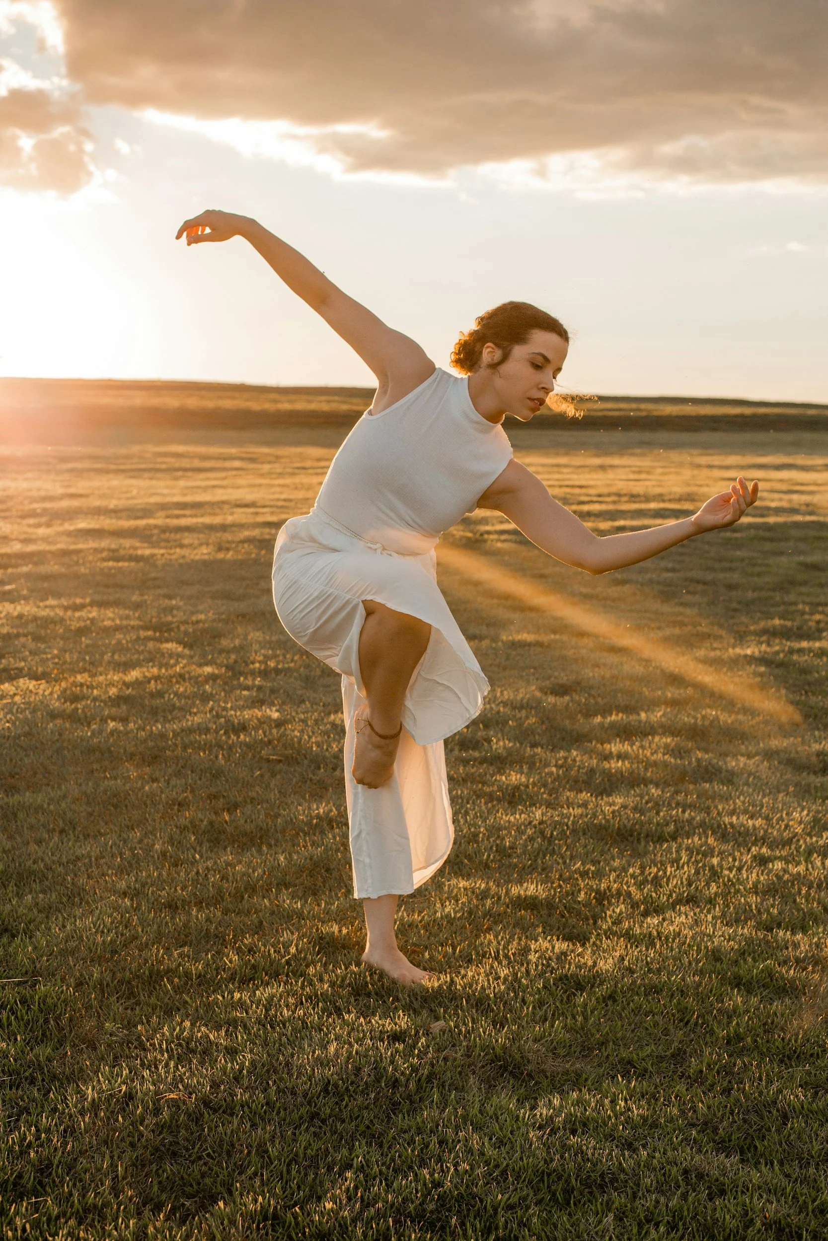 Woman dancing in a field with golden light.