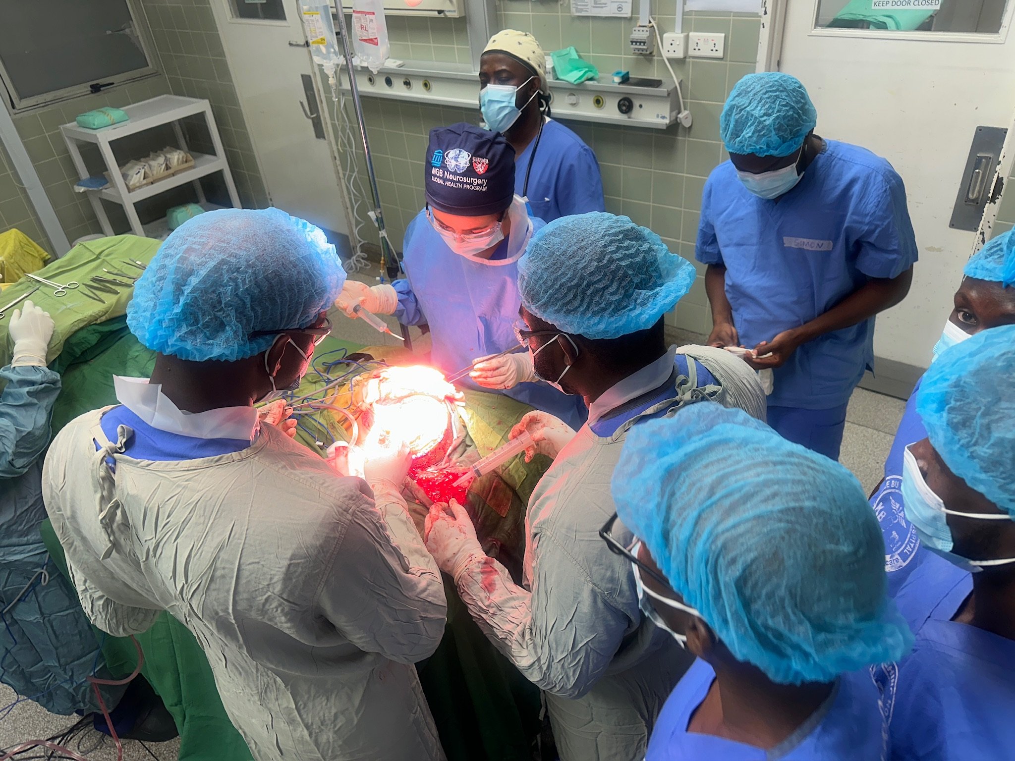 Medical team performing surgery in an operating room, with surgeons, nurses, and medical staff focused on the patient, surrounded by surgical tools and medical equipment.