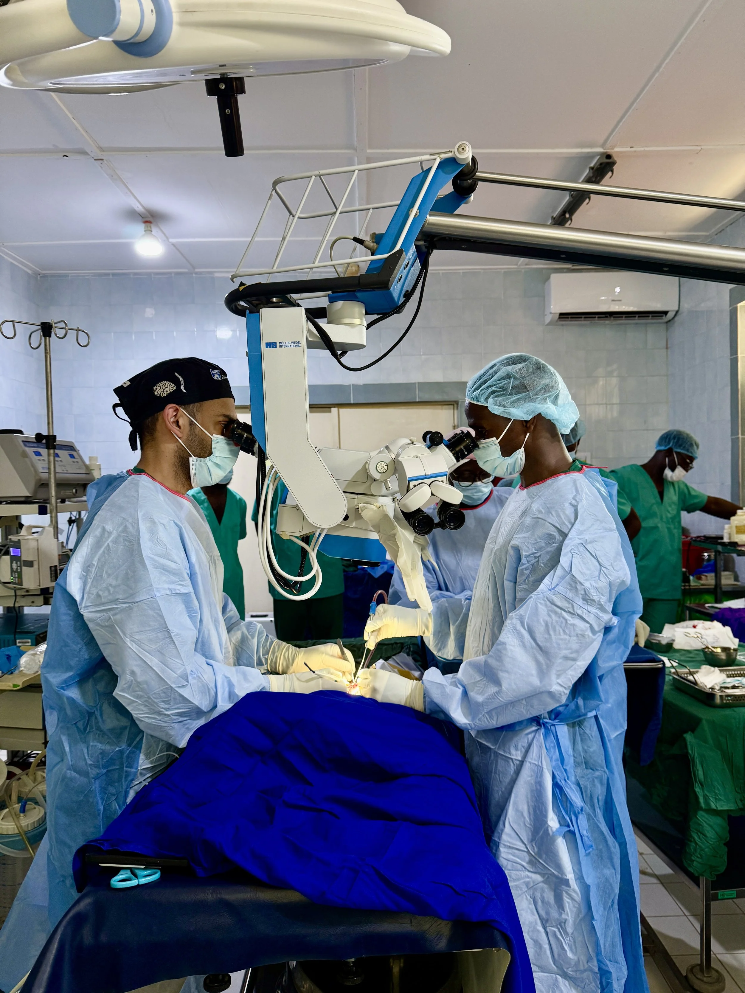 Medical team performing surgery in an operating room with a microscope and surgical instruments.