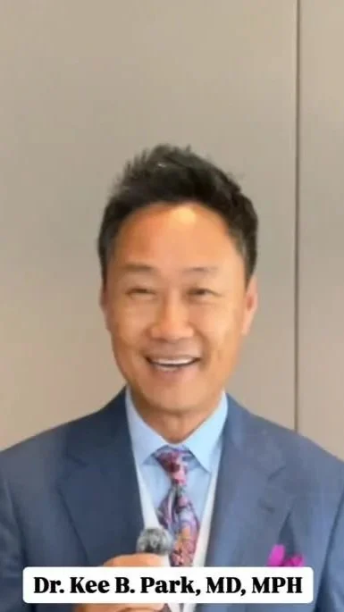 A man wearing a blue suit, light blue shirt, and patterned tie, smiling and holding a microphone. Text at the bottom reads "Dr. Kee B. Park, MD, MPH."