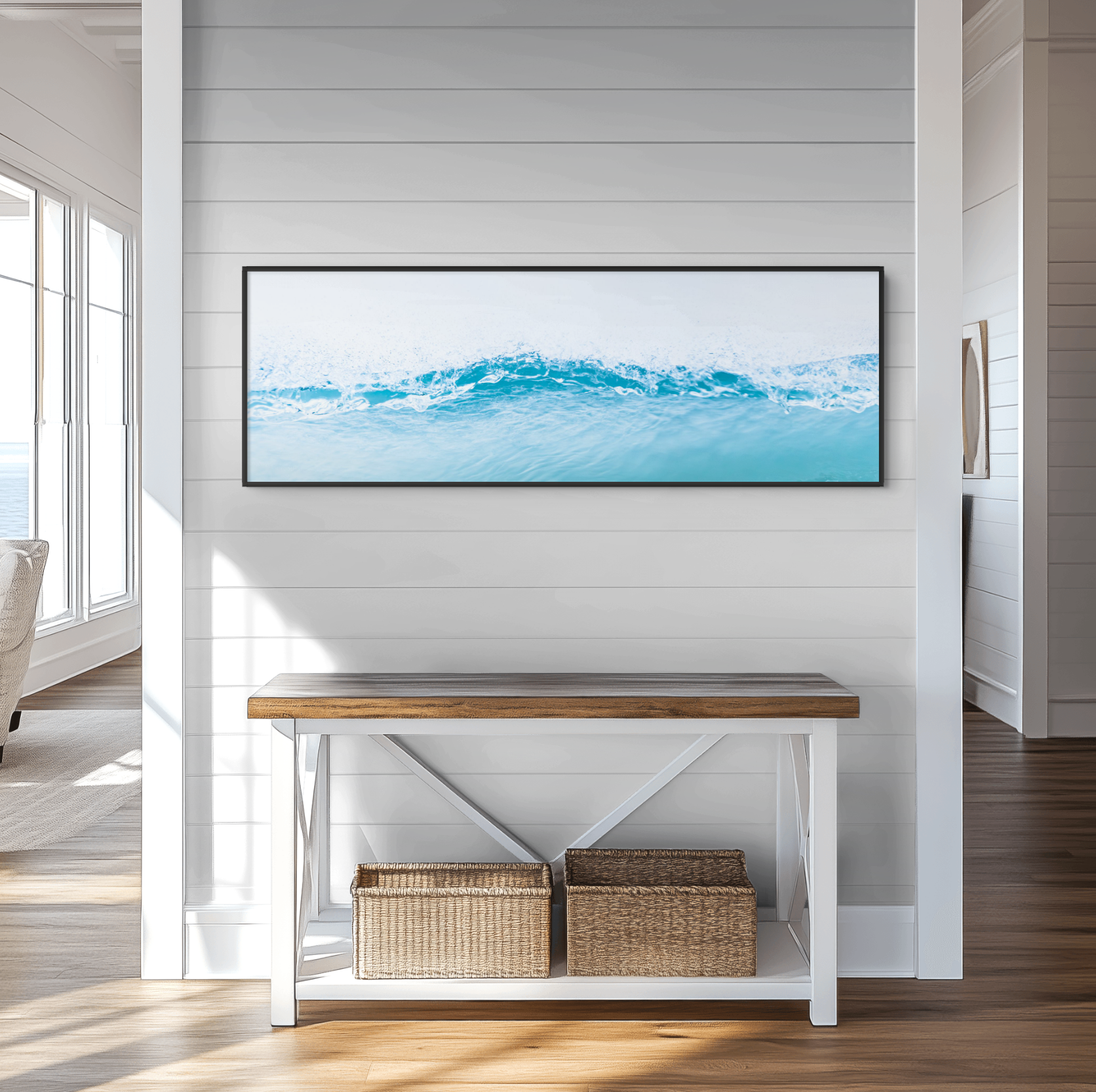 Living room with white paneled walls, a large window with sunlight, a flat-screen TV displaying water waves, a white console table with a wooden top, and two baskets underneath, situated on a wooden floor.