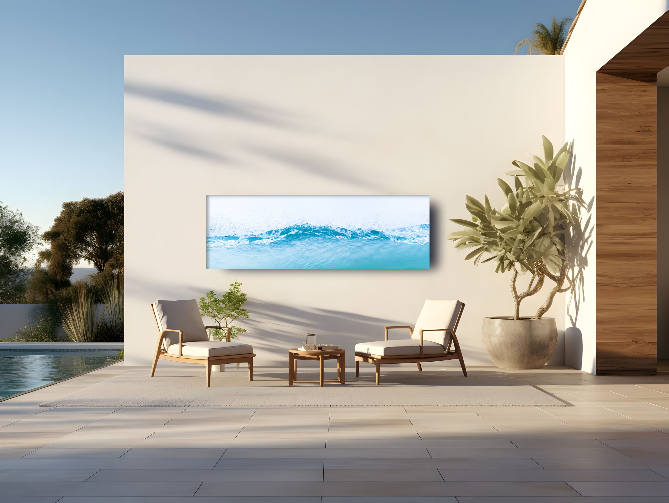 Modern outdoor patio with white lounge chairs, a large planter with a leafy tree, a white wall with a mounted flat-screen TV showing water, and a background of trees and blue sky.