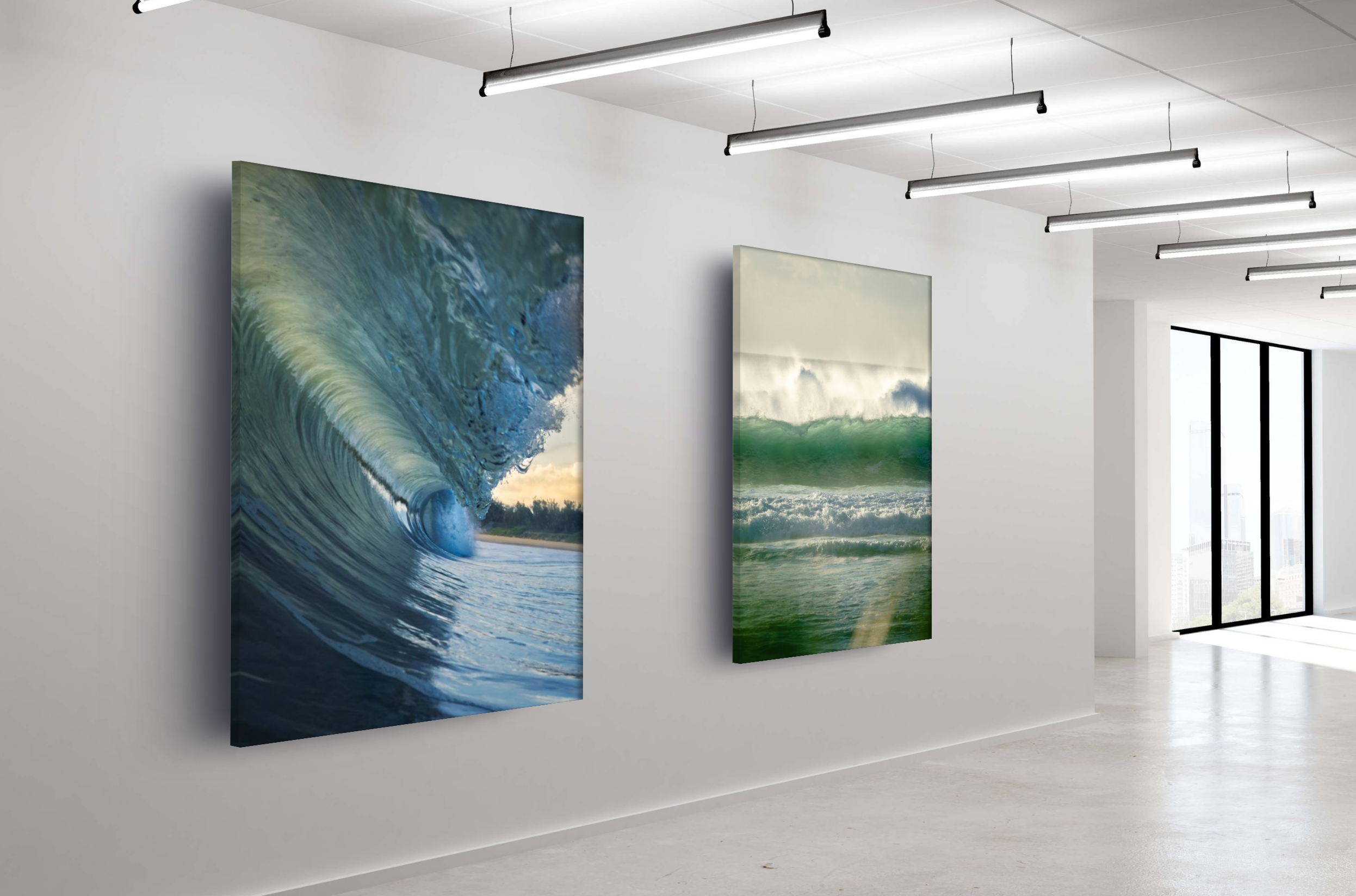 Interior view of an art gallery displaying two large ocean-themed paintings on a white wall, with a large window on the right side allowing natural light in.