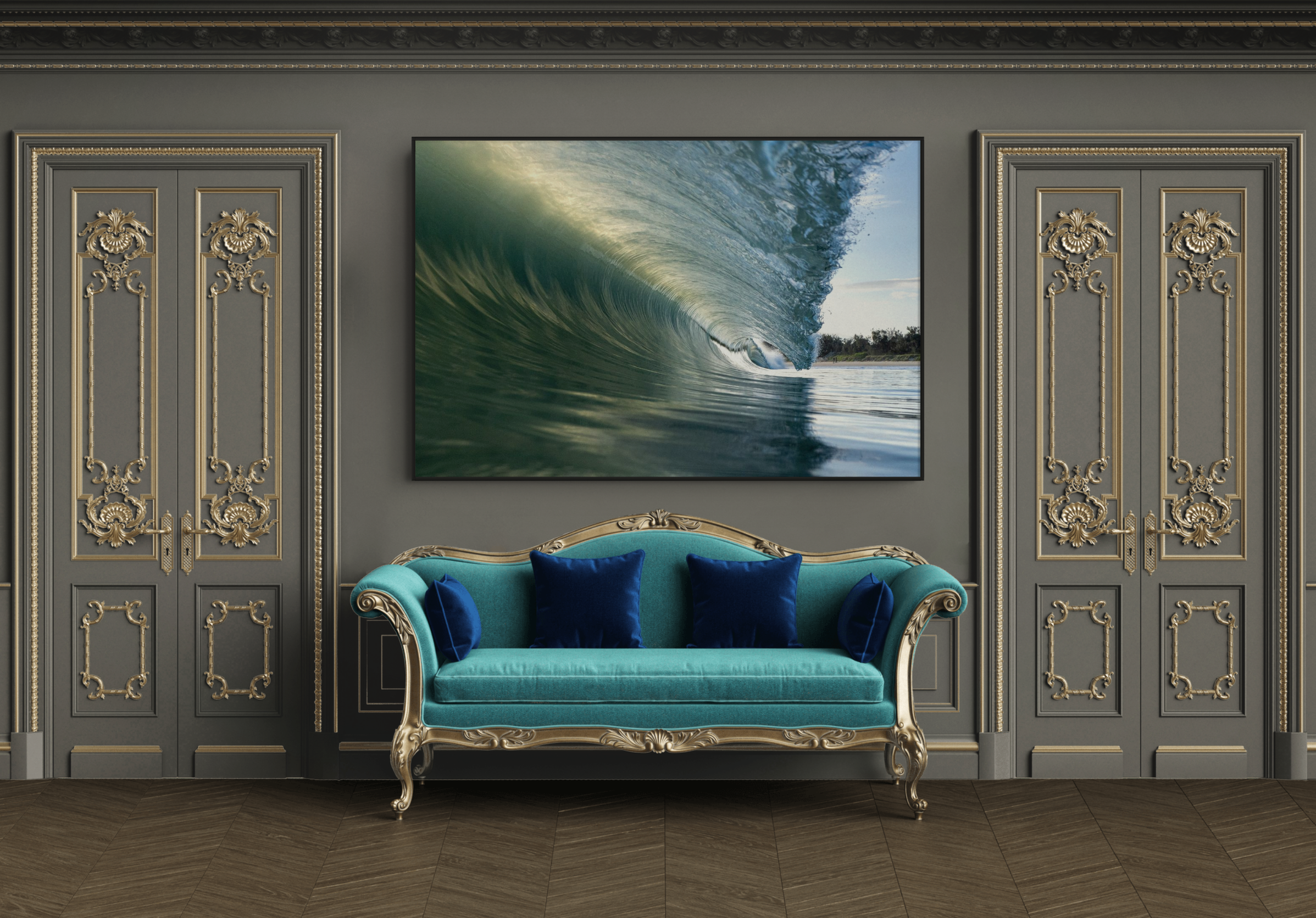 Elegant interior with gray walls and gold-trimmed double doors. A large framed photograph of an ocean wave hangs above a vintage teal and gold sofa with blue velvet cushions. Dark wood flooring completes the luxurious setting.