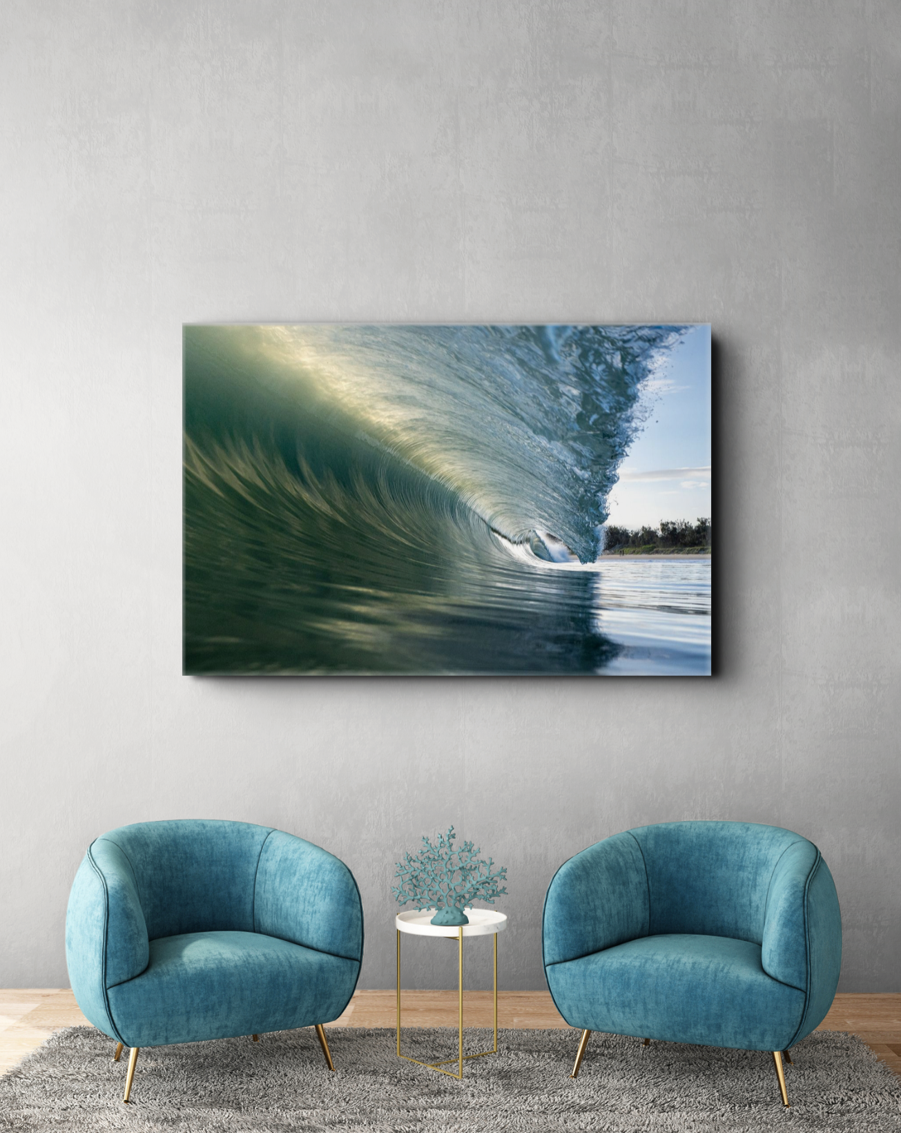 Living room with a large wall art of an ocean wave, two teal velvet armchairs, a small round side table with a decorative coral piece, on a gray rug.