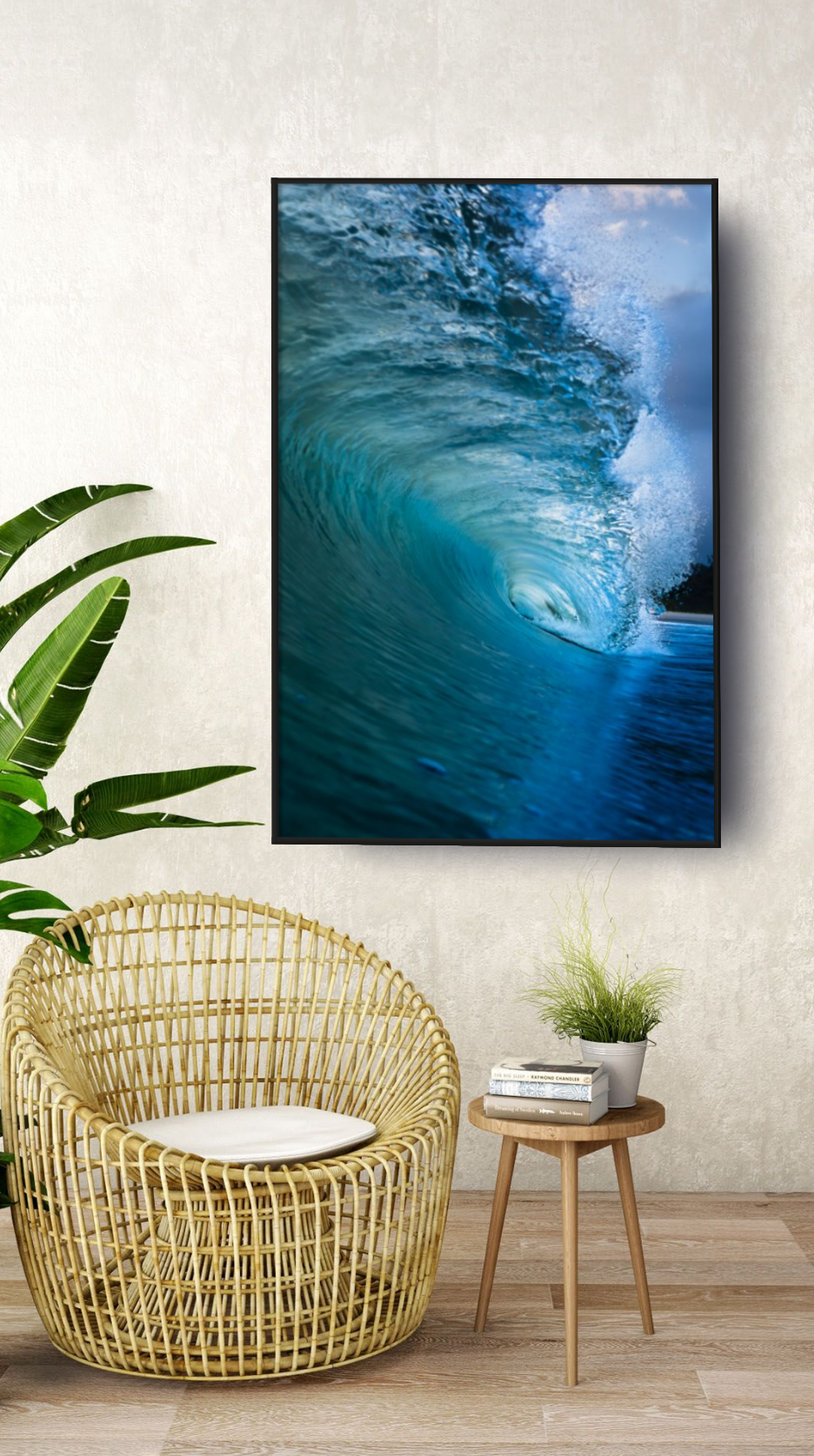 Interior of a modern living room with a large flat screen TV displaying a powerful ocean wave, a rattan chair with a cushion, a small wooden side table with a potted plant and books, and a large green leafy plant on the left side. The room has light-colored walls and wooden flooring.