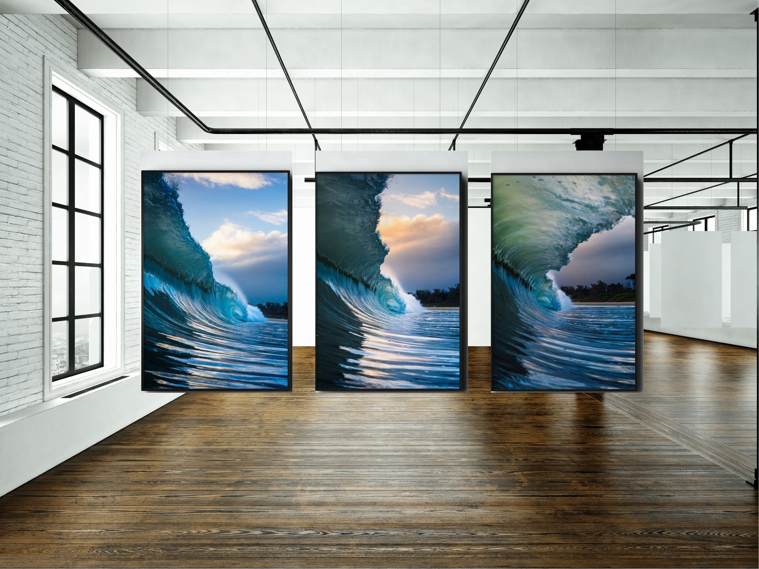 Display of multiple digital screens showing ocean waves inside a gallery with white brick walls and large windows.