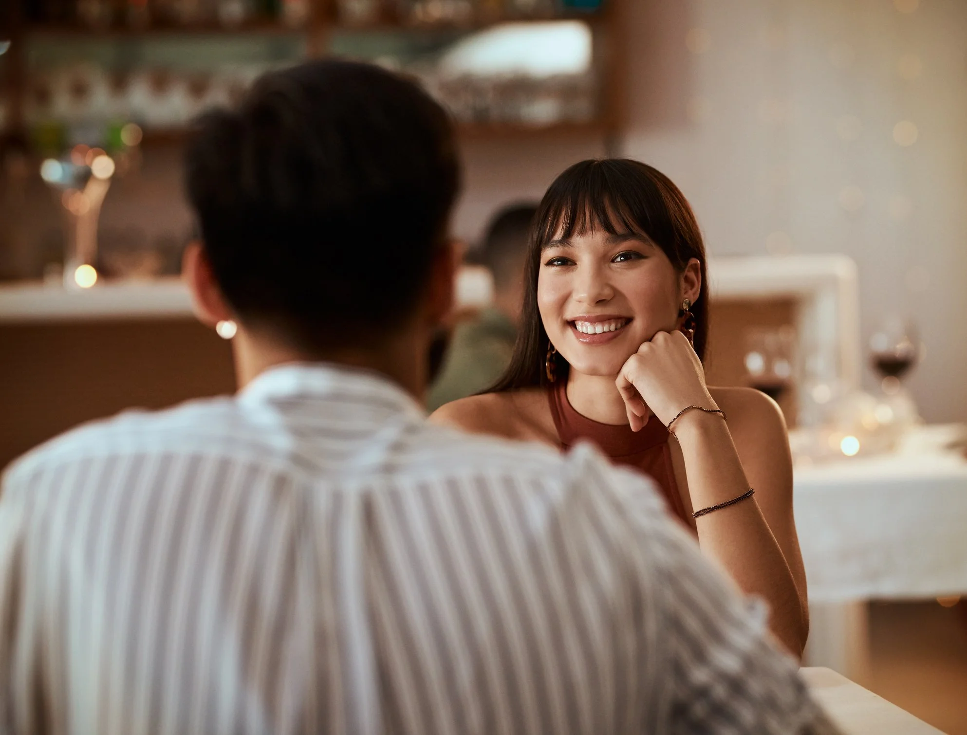 A woman smiling and looking at a man in a restaurant or café setting.