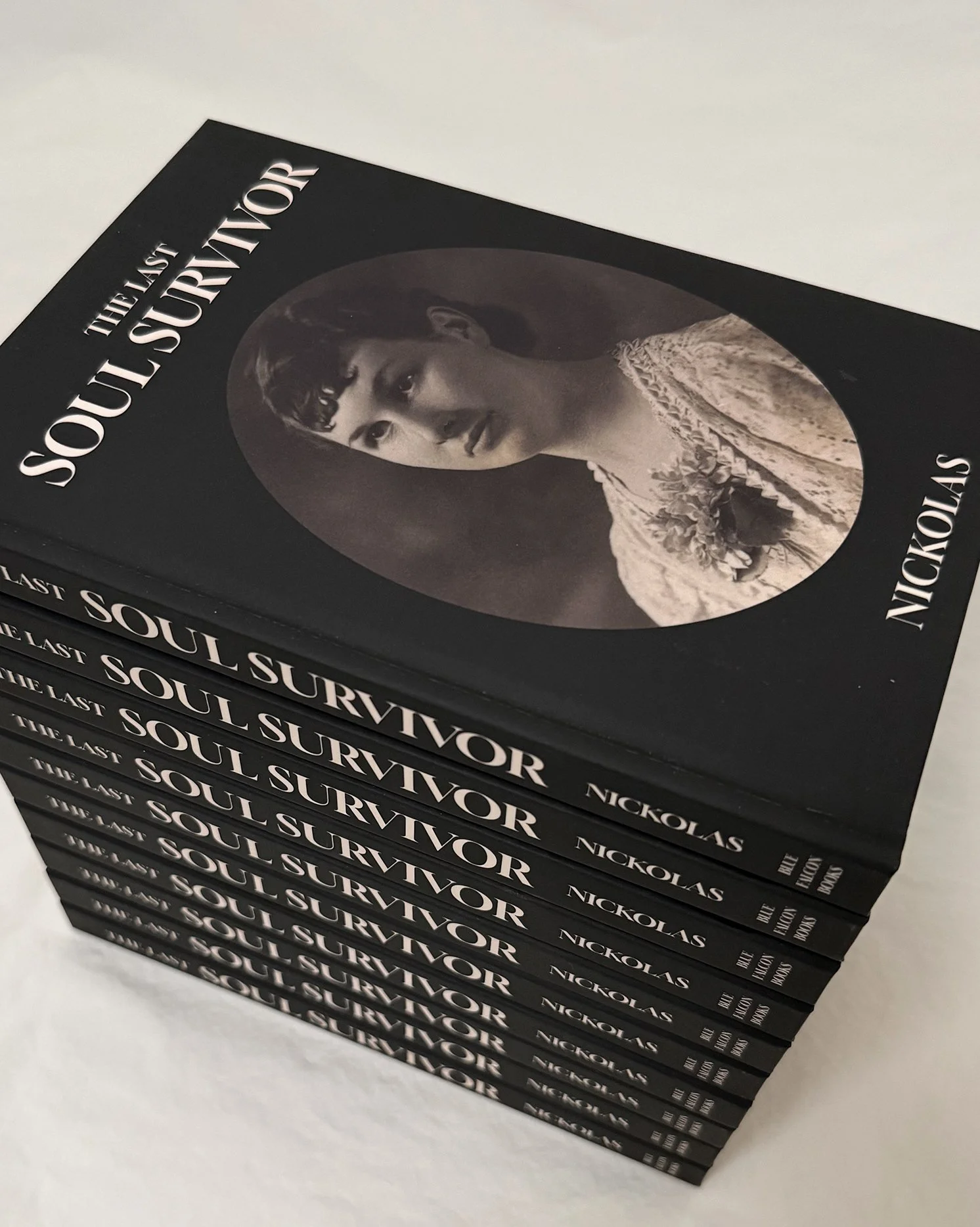 Five copies of the book titled "The Last Soul Survivor" by Nickolas stacked on a white surface, showing the cover featuring a black and white photograph of a woman with short dark hair, wearing a light-colored lace dress with flowers, framed in an oval.