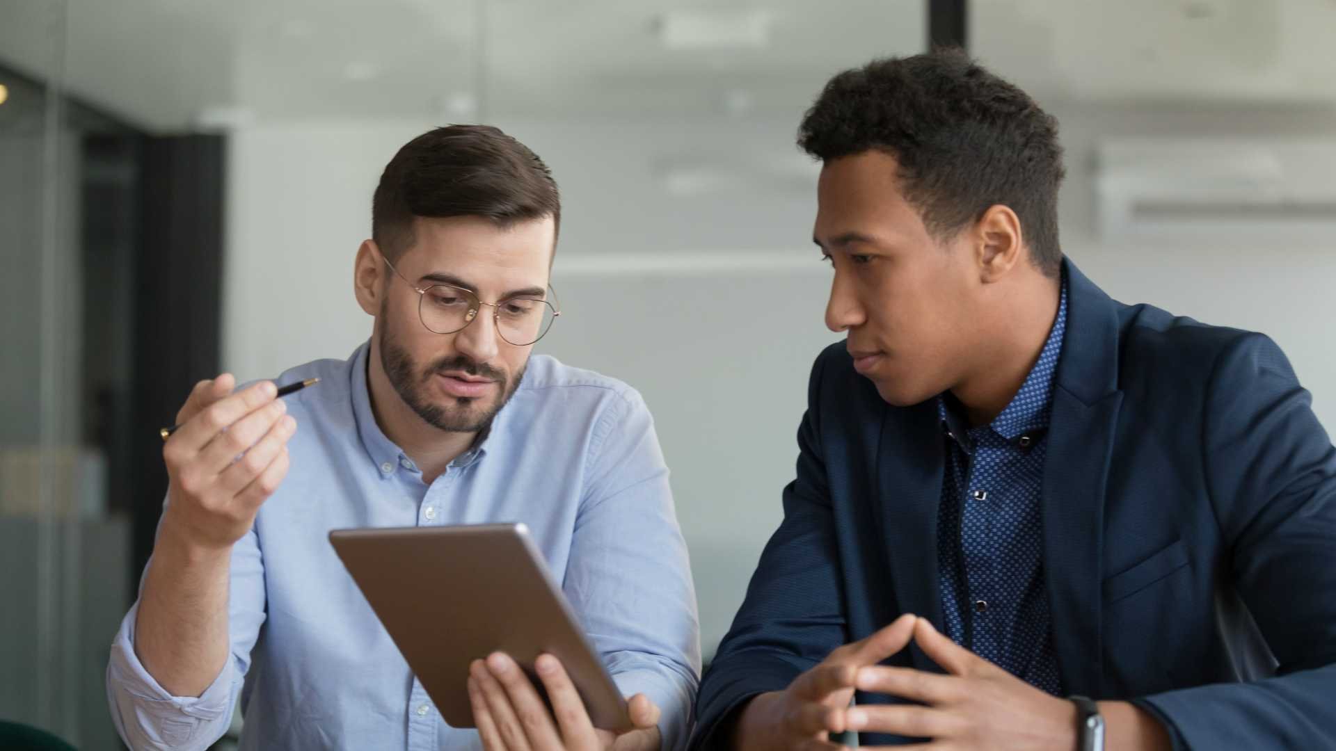 Two men in business attire sitting at a table having a coaching session.