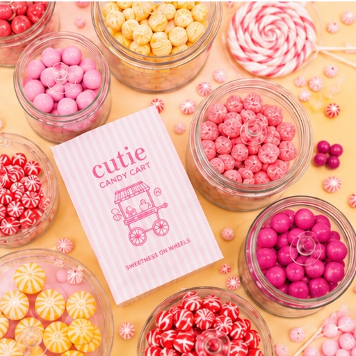 A variety of pink, red, and yellow candies in glass jars surrounding a pink and white striped candy cart card that reads "cutie candy cart" and "sweetness on wheels."