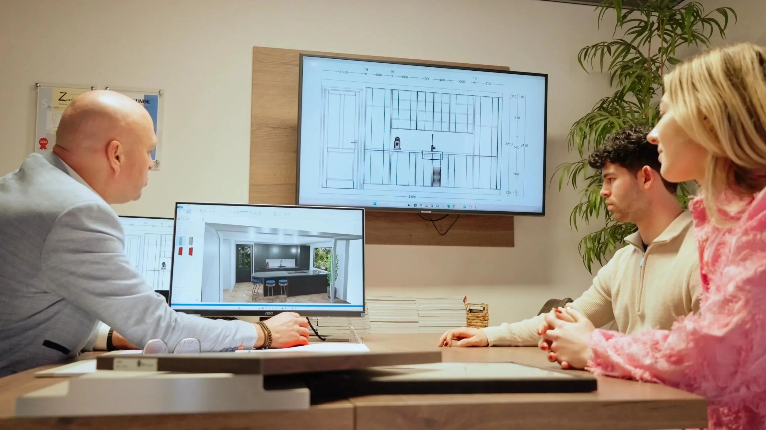 Homeowner, designer, and CAD drafter in a meeting room, looking at architectural plans and reviewing slab layouts on a computer screen.
