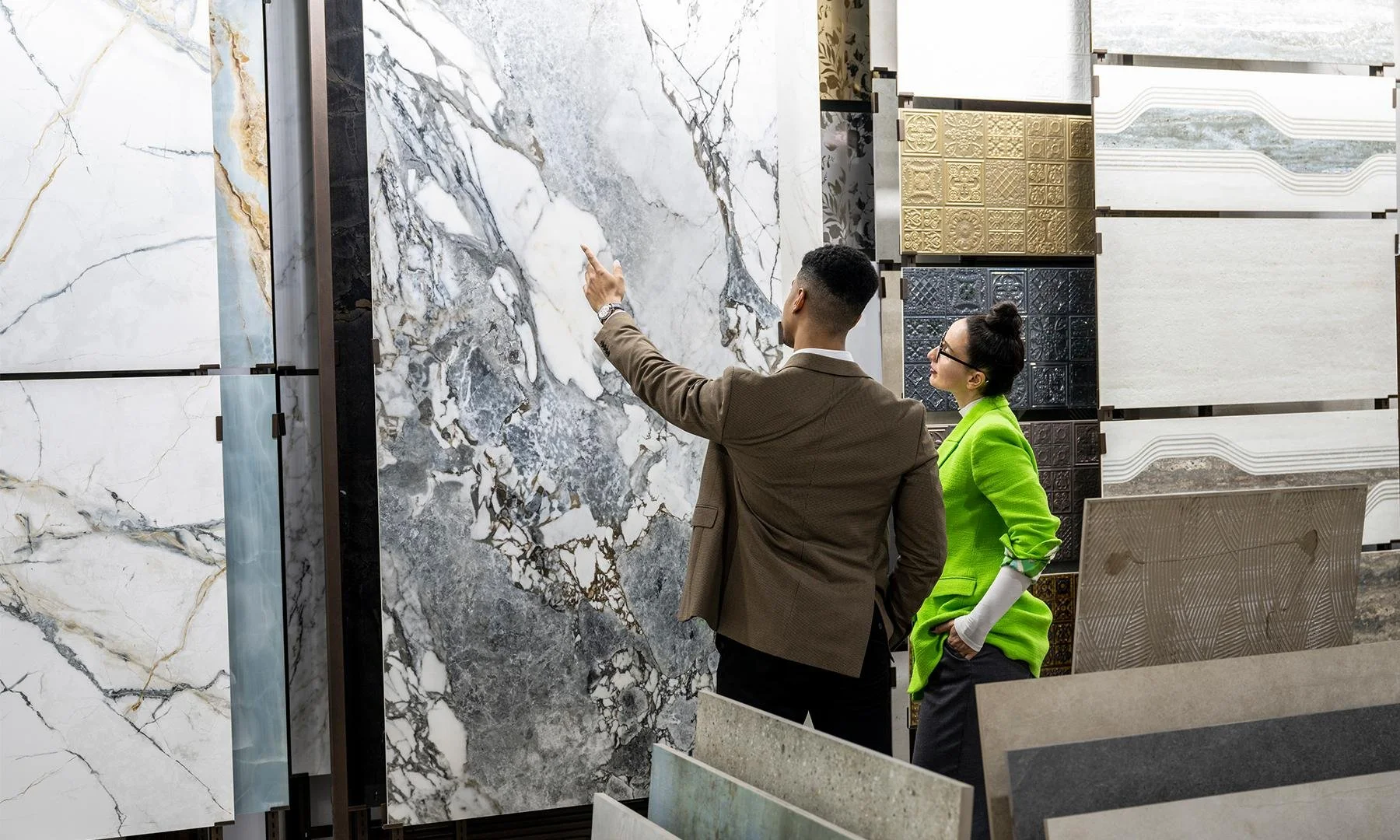 Designer and homeowner in the showroom of a slab vendor, looking at large quartzite and marble slabs to select for their home renovation project.