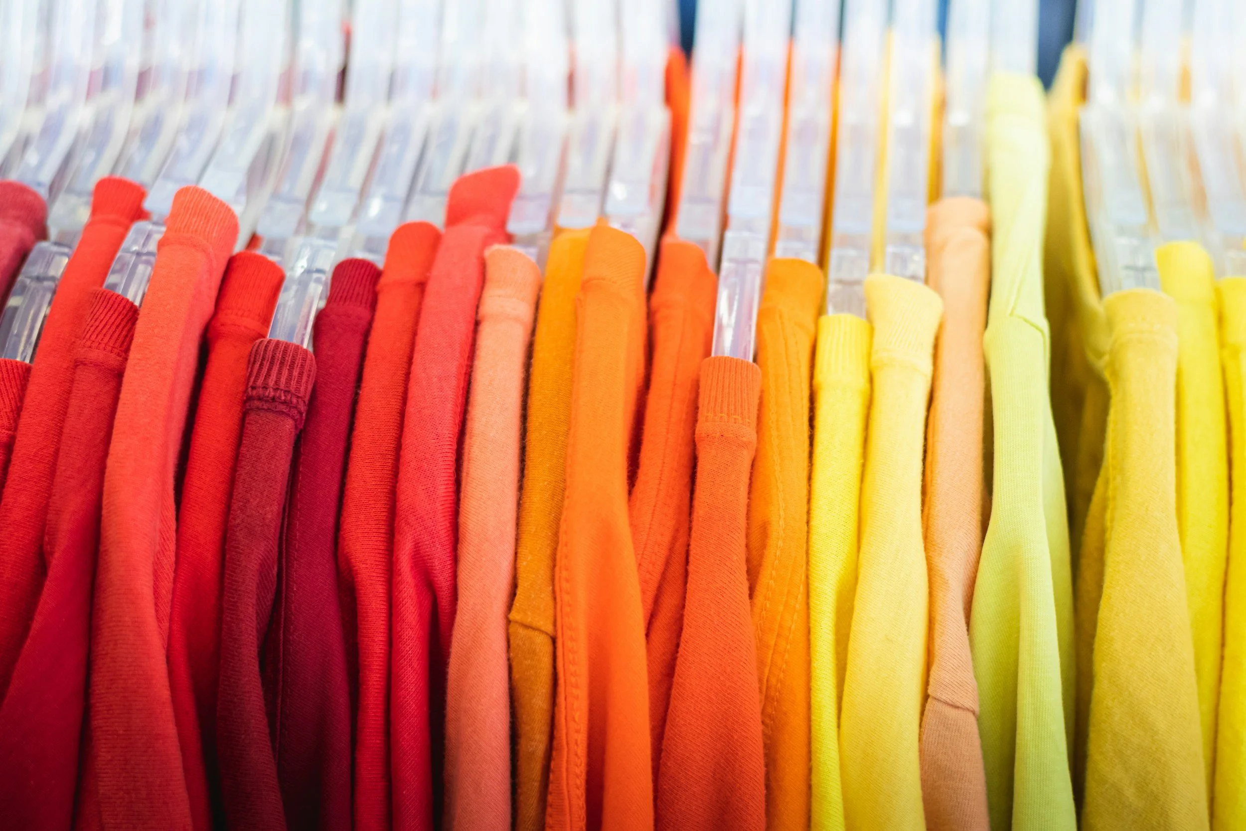 Colorful array of hoodies or sweatshirts organized by color from red to yellow.