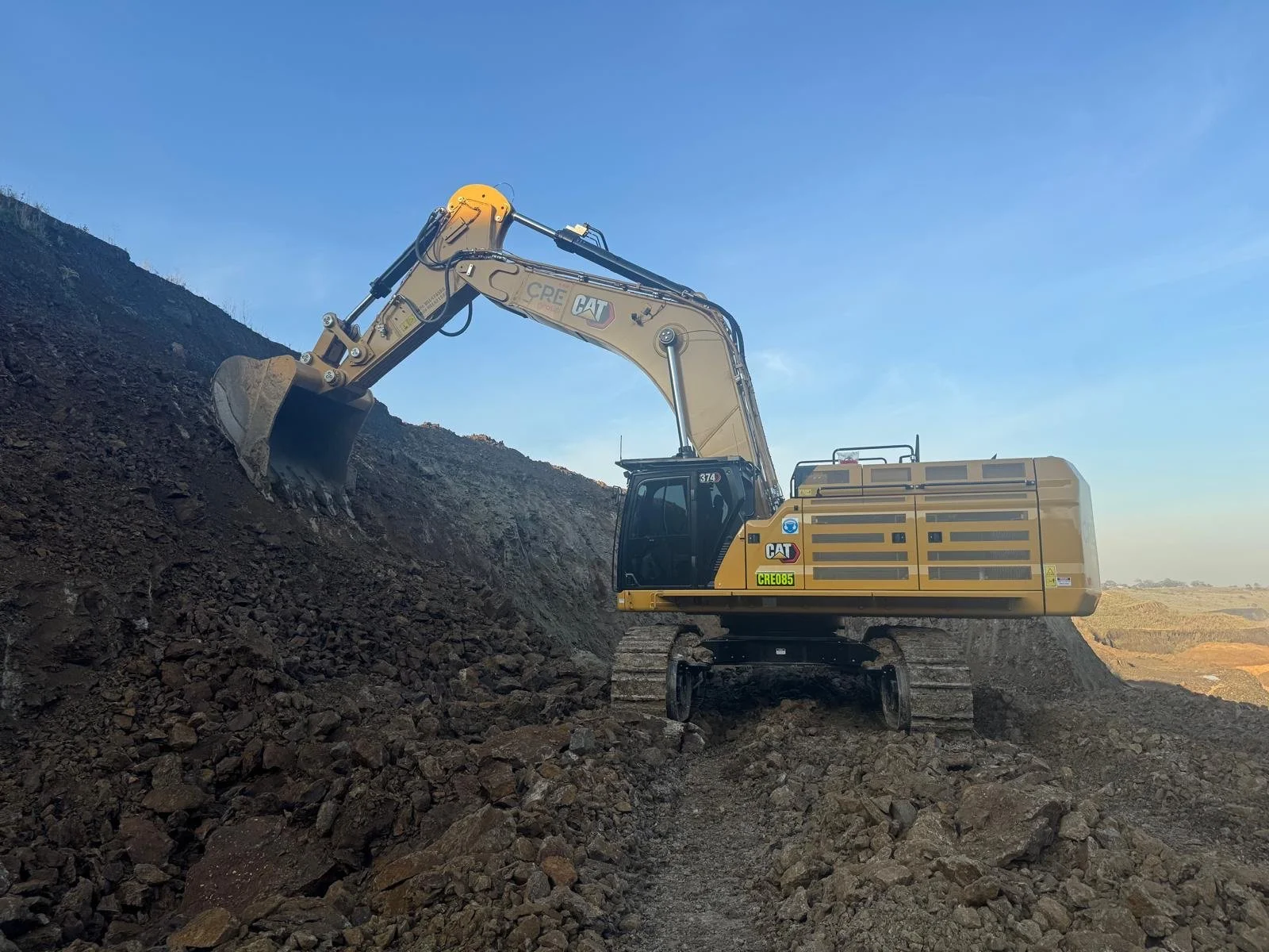Photo of a yellow CAT digger on a work site with clear blue skies 