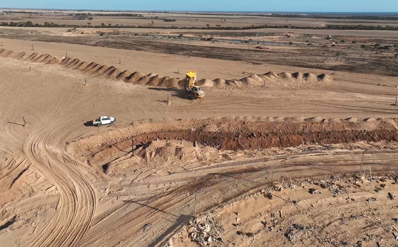 aerial drone shot of work site with ute, trucks and dirt