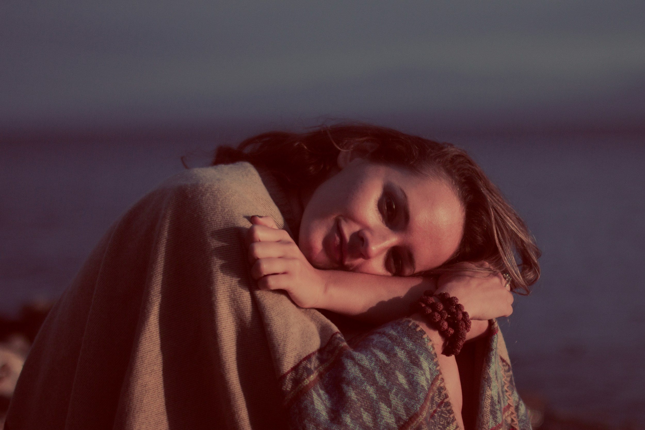 A woman resting her head on her arms, with a gentle smile, in a softly lit environment