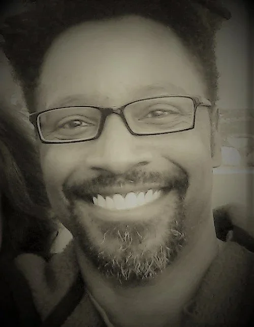 A man with glasses, a beard, and a big smile.
