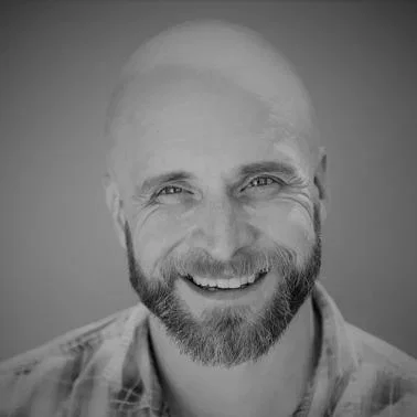Black and white photo of a smiling man with a beard and shaved head