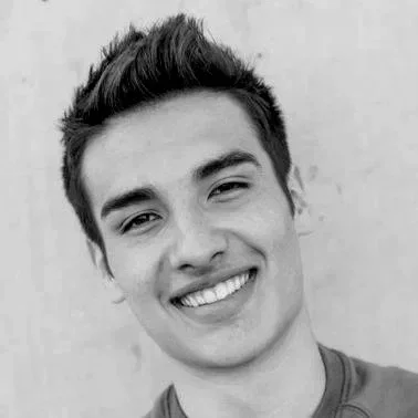 Black and white photo of a young man smiling, looking at the camera.