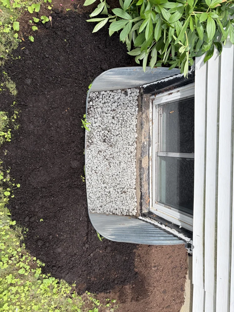 Clean window well with fresh stone and graded soil