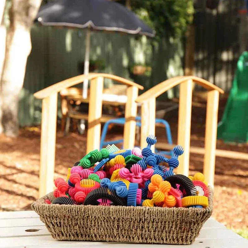 Basket of colourful pom-poms ready for an outdoor sensory activity