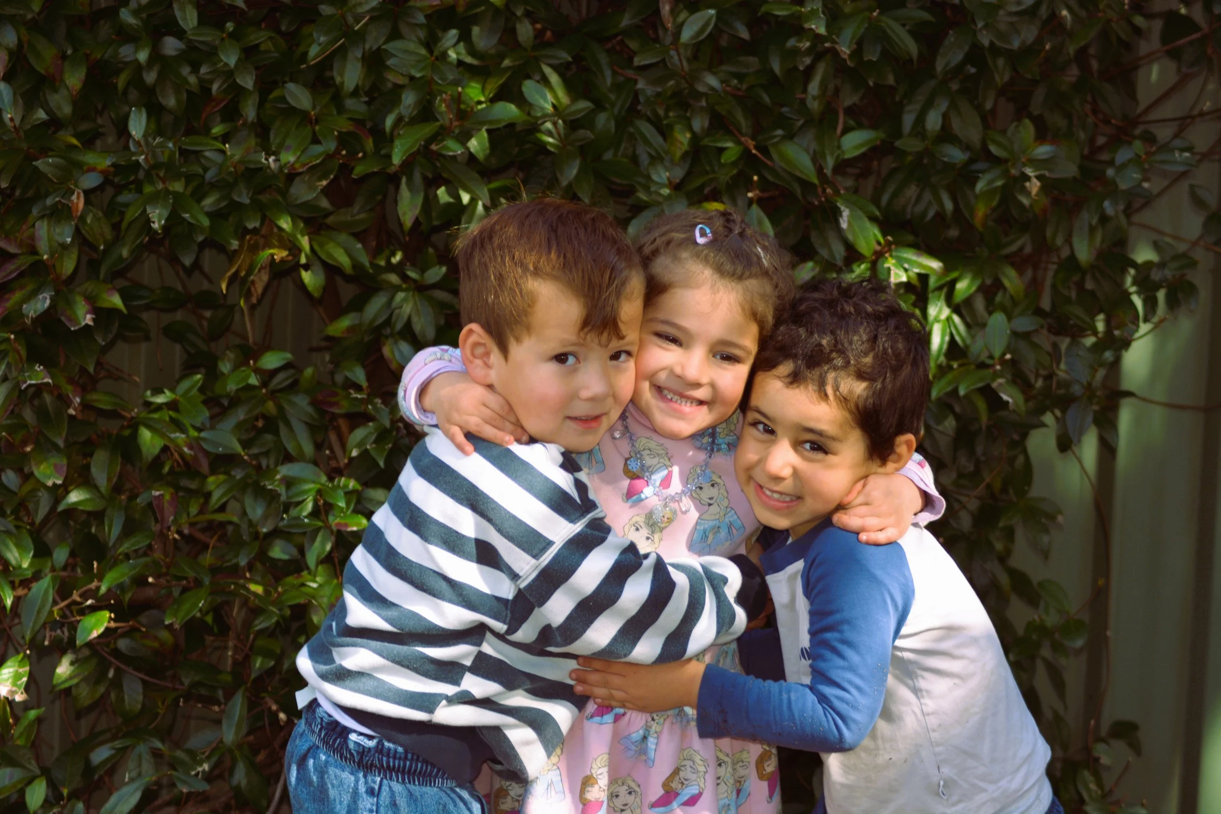Three young friends sharing a hug in the Bunny Cottage garden