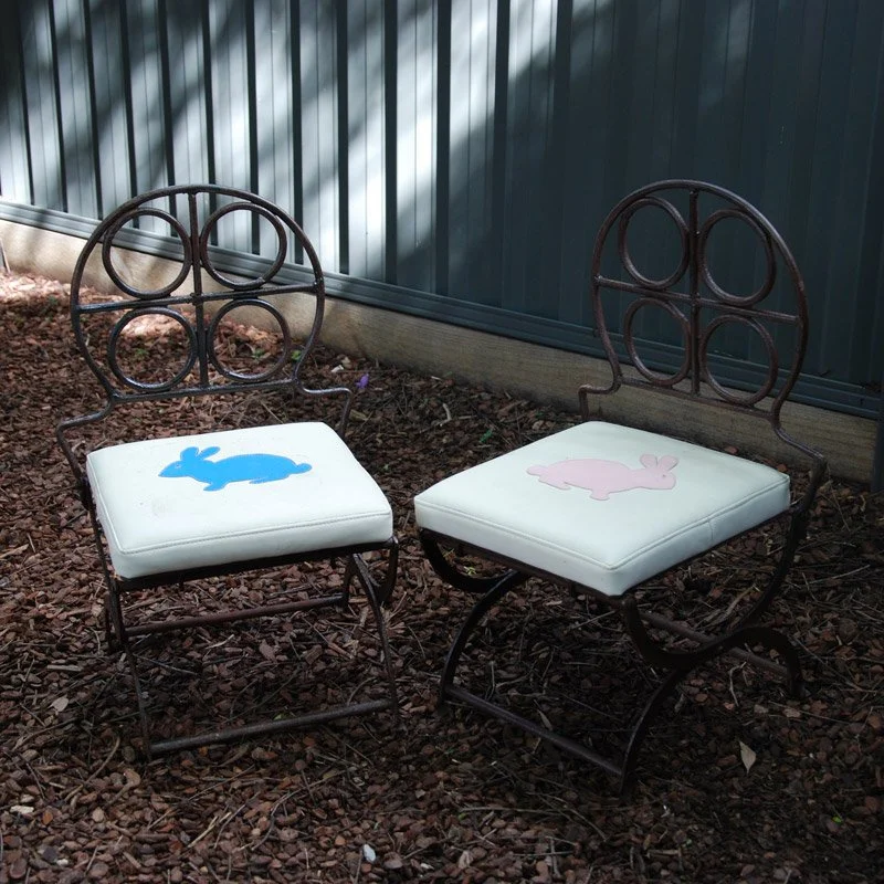 Two little garden chairs with bunny cushions in the play yard
