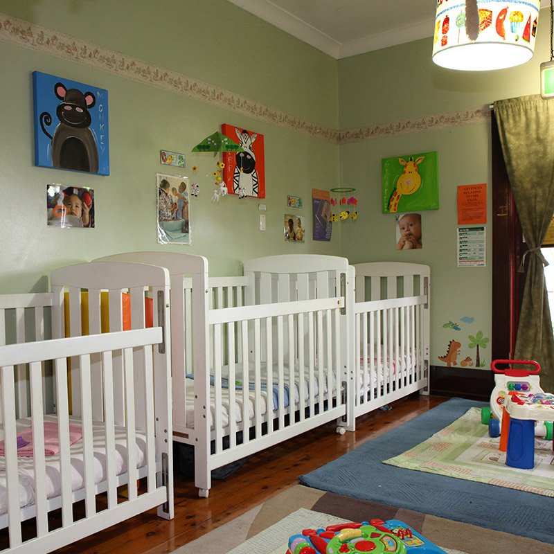 Bright nursery with white cots and colourful animal artwork