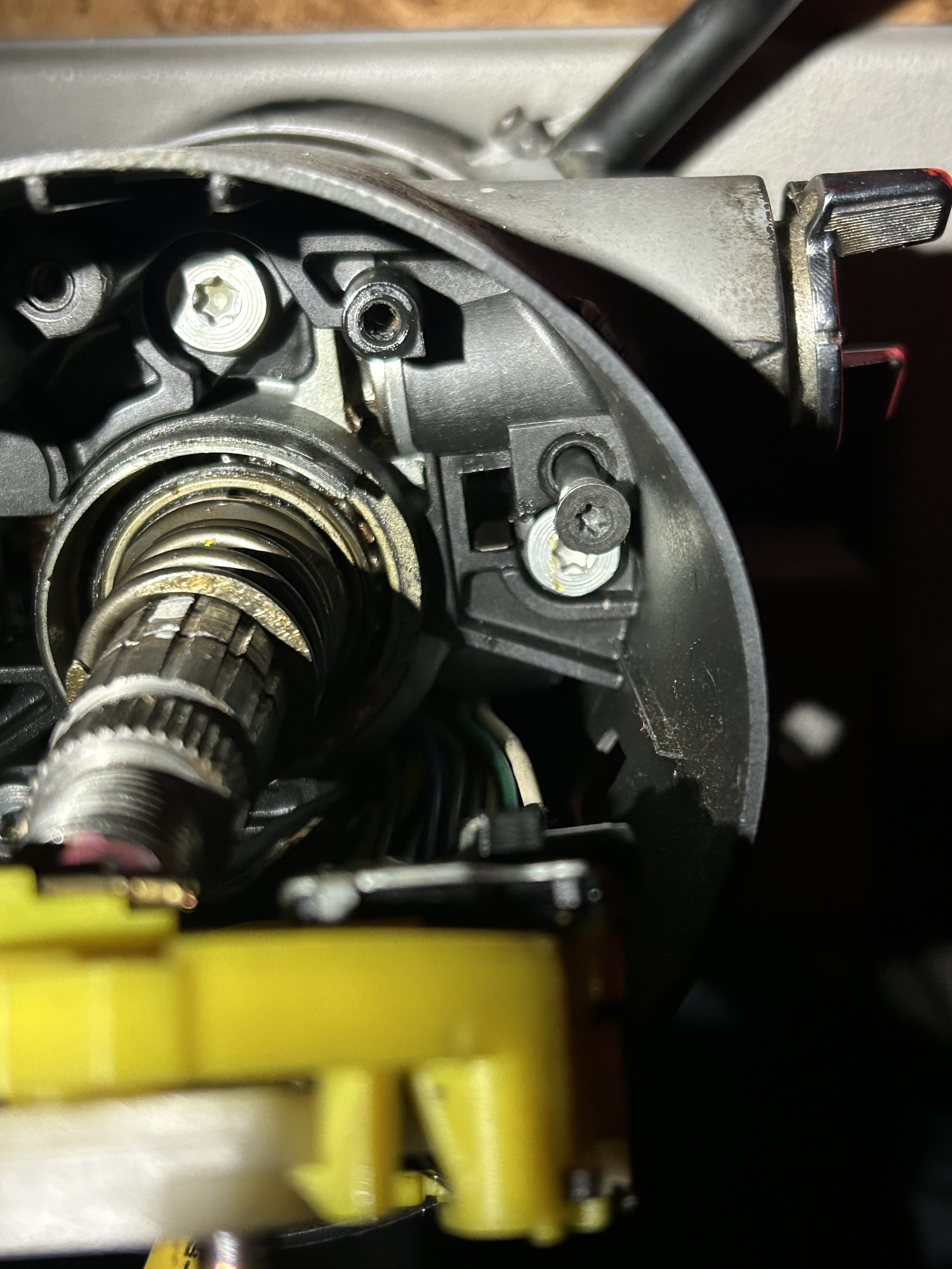Close-up of an internal mechanical part, possibly a gear or motor component, with visible screws, metal gears, and wires.