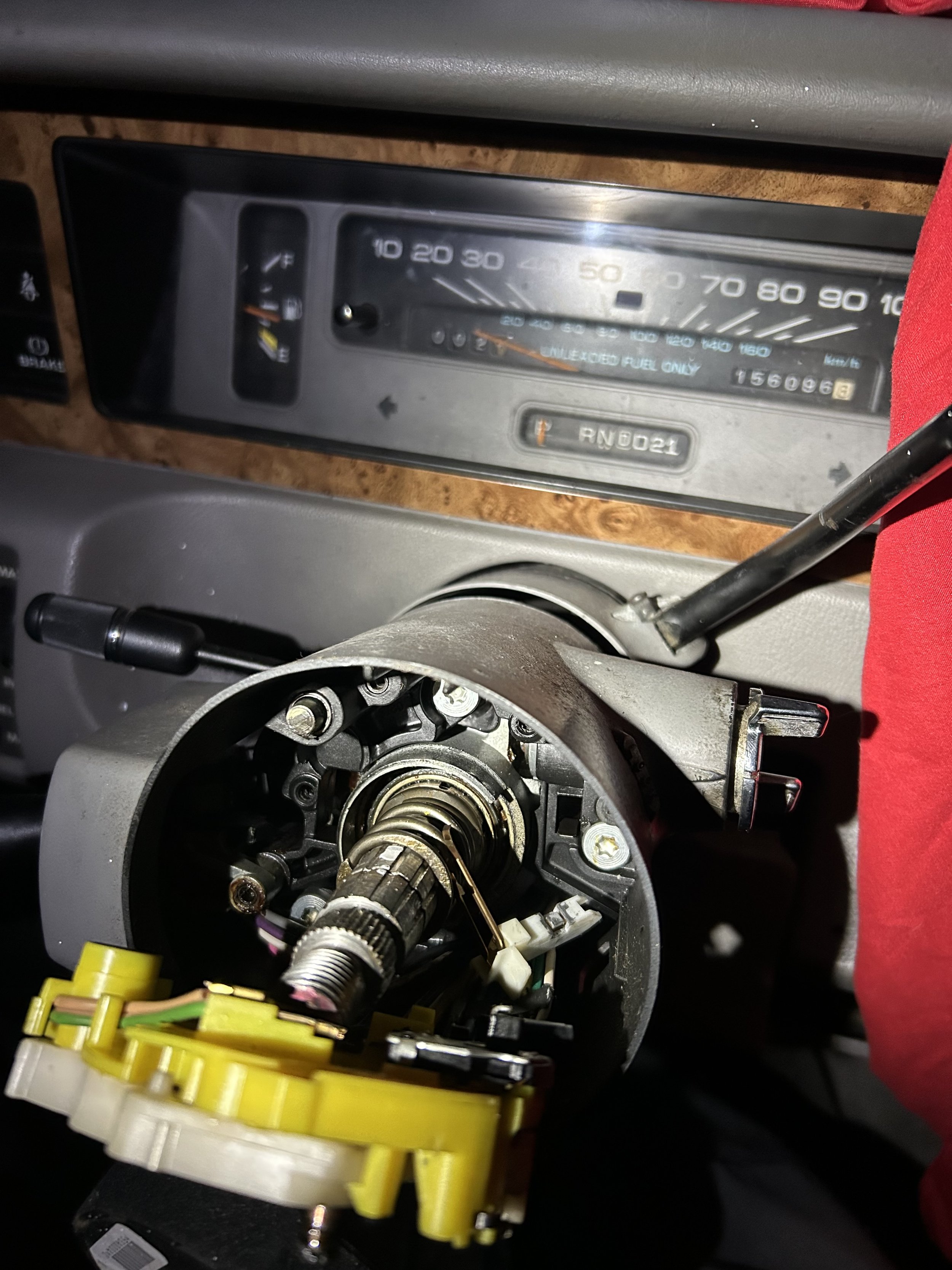 The image shows a close-up view of a disassembled car dashboard with exposed wiring and internal components, including a partially visible speedometer.